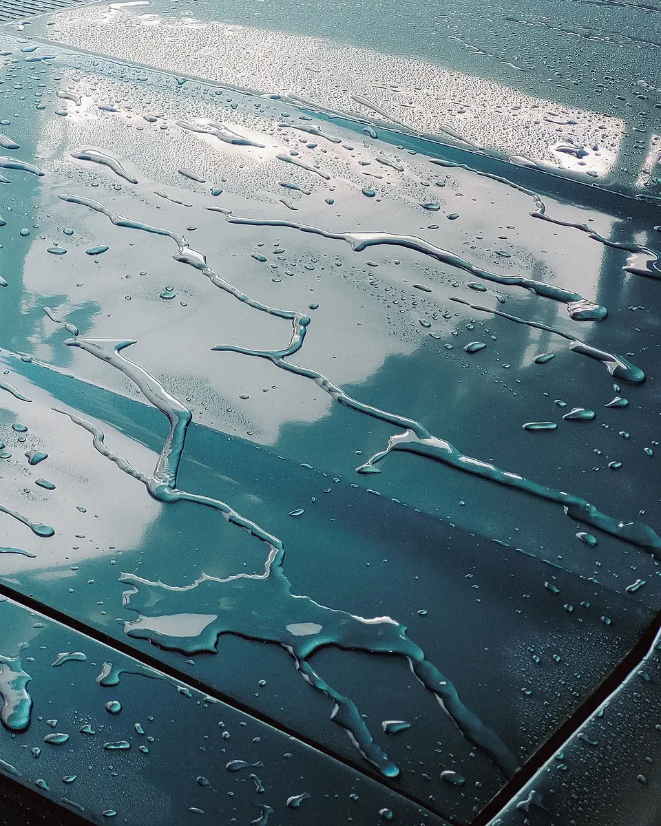 Water drops on a hood reflecting the sky