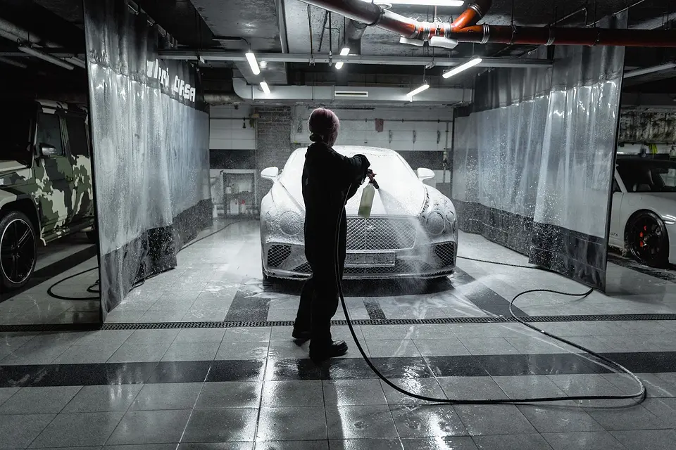 Foam cannon covering a car in a bright garage