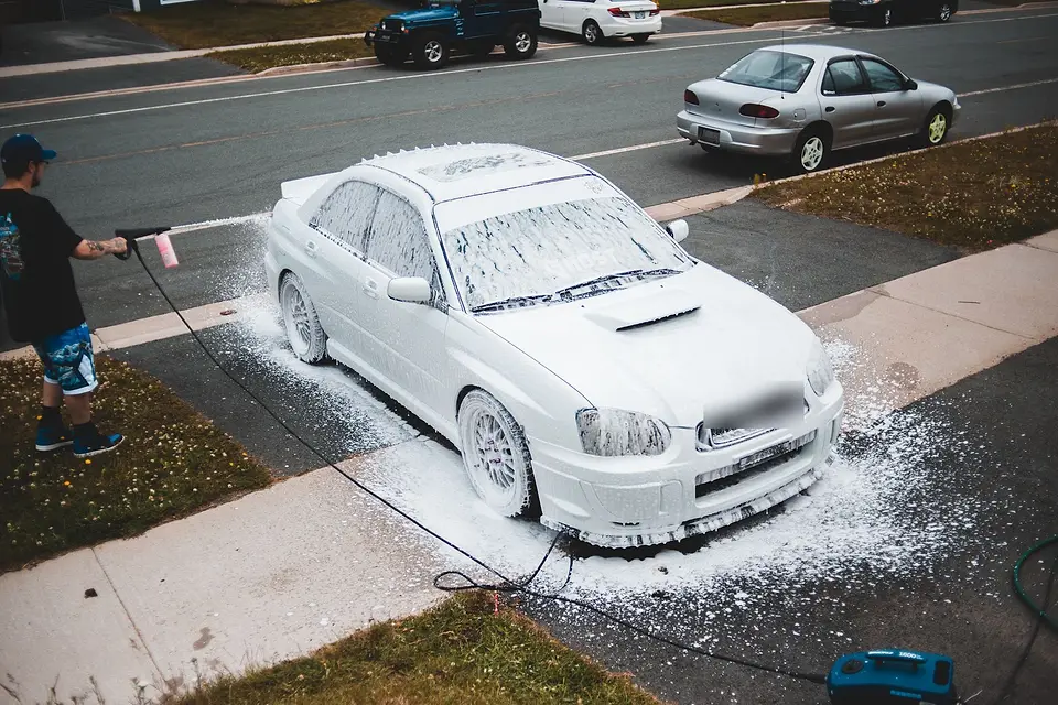 White car covered in snow foam in a home driveway
