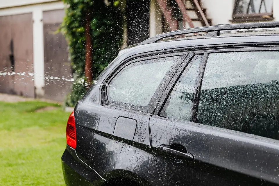 Rinse water sheeting off a dark wagon in a backyard