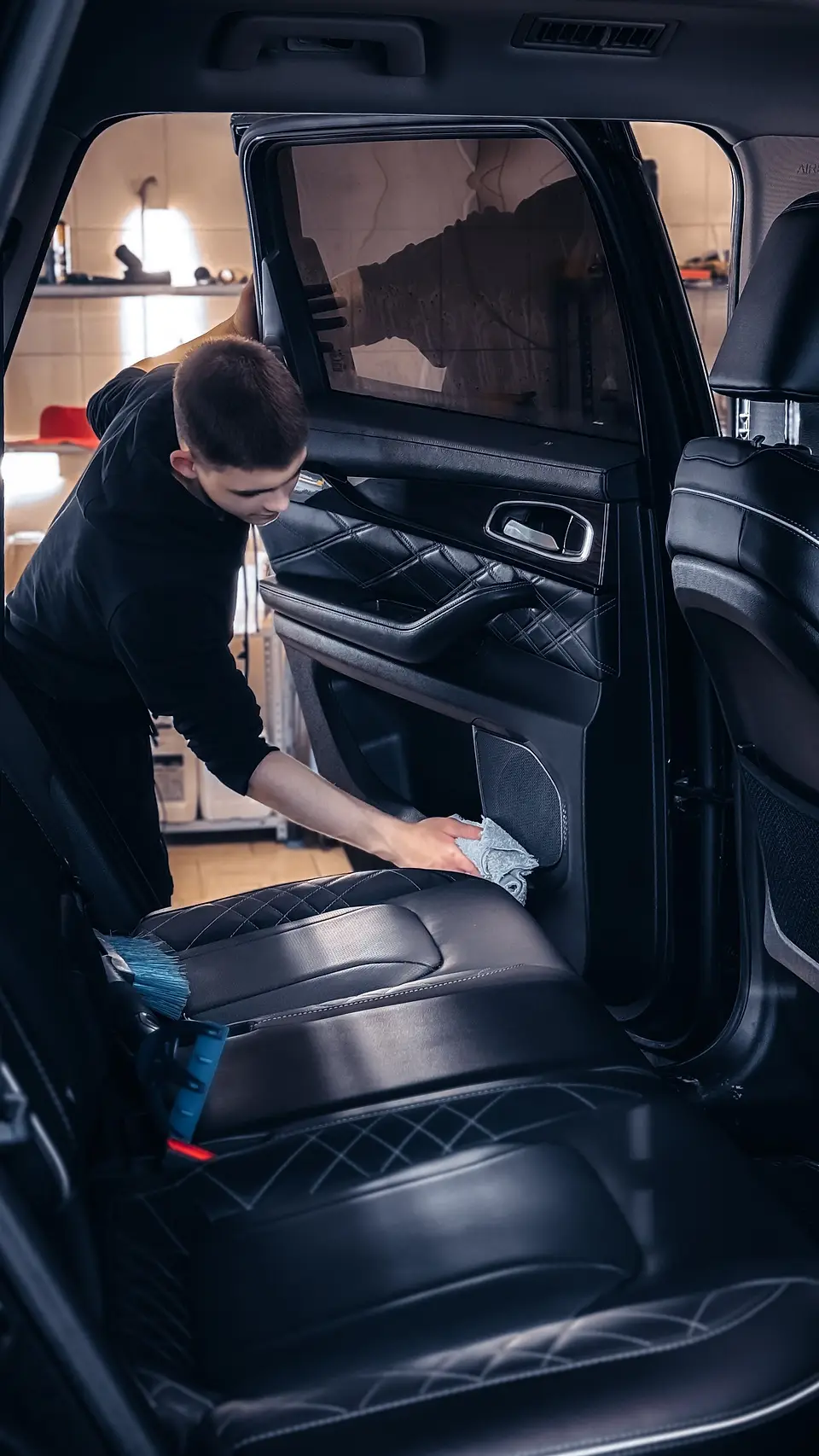 Detailer wiping down a door panel inside a car