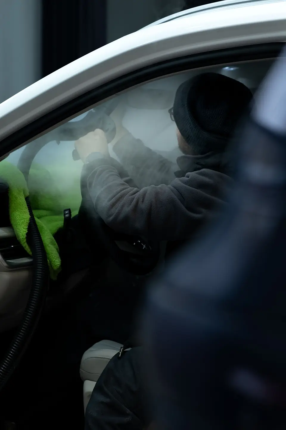 Gloved hand cleaning tight spots inside a car