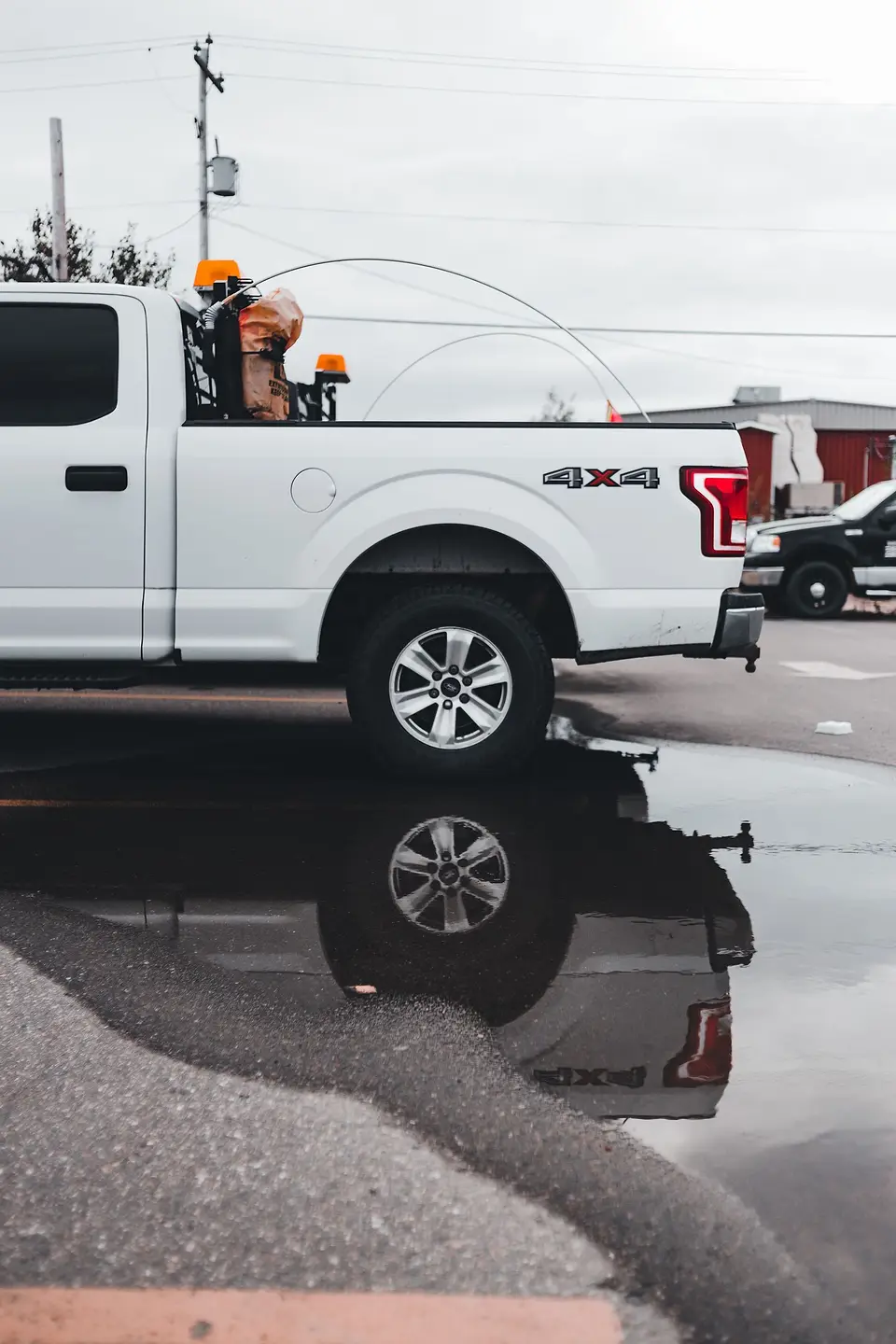 Clean white pickup reflected in a puddle