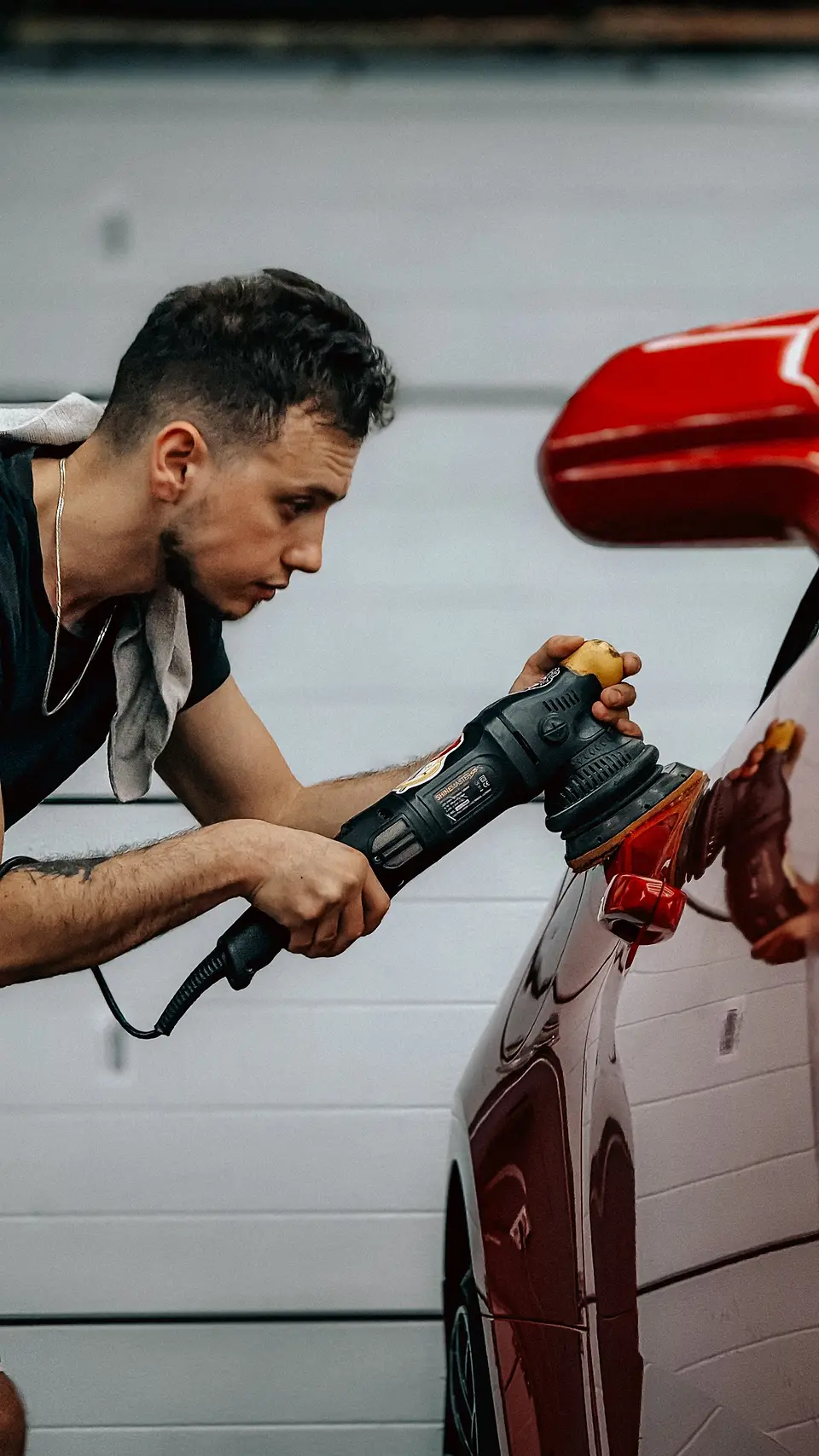Detailer polishing a red car with a dual-action polisher
