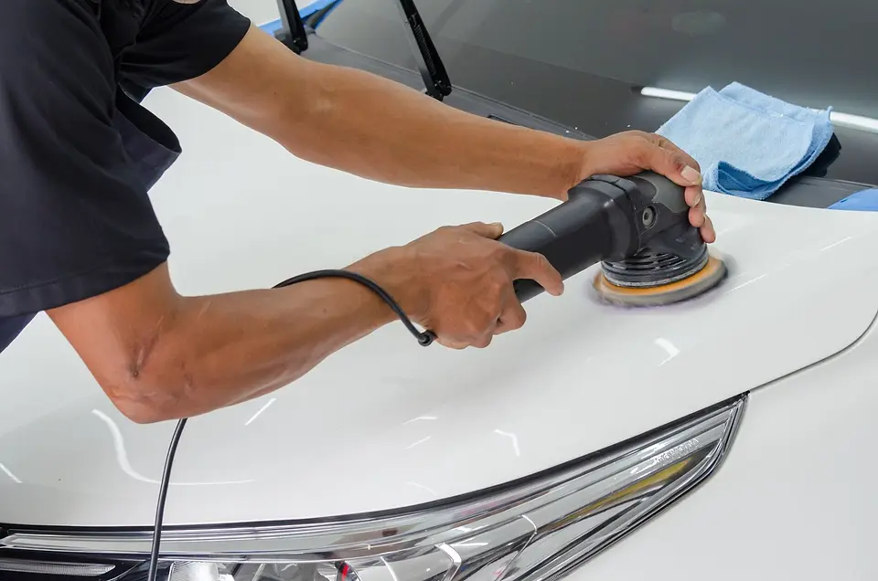 Polisher working on the hood of a white car